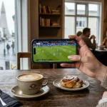 Farsími á borði á kaffihúsi í Reykjavík með fótboltaleik á skjánum og HM 2026